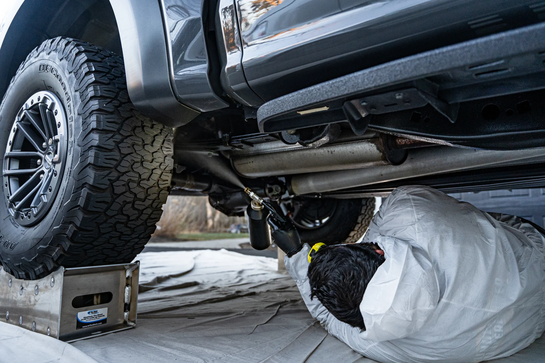 UnderCover technician applying undercoating beneath a raised pickup at the customer&rsquo;s location